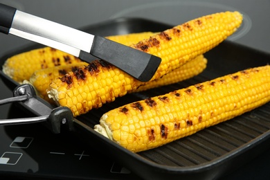 Photo of Cooking fresh corn cobs on grill pan, closeup