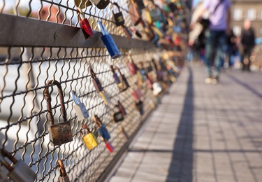 Love locks hanging on bridge railing on sunny day