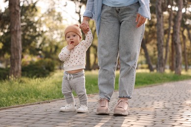 Photo of Mother supporting her baby while he learning to walk outdoors, closeup