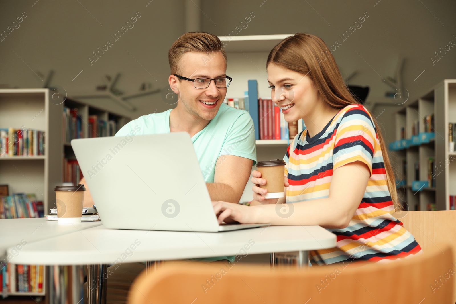 Photo of Young people discussing group project at table in library