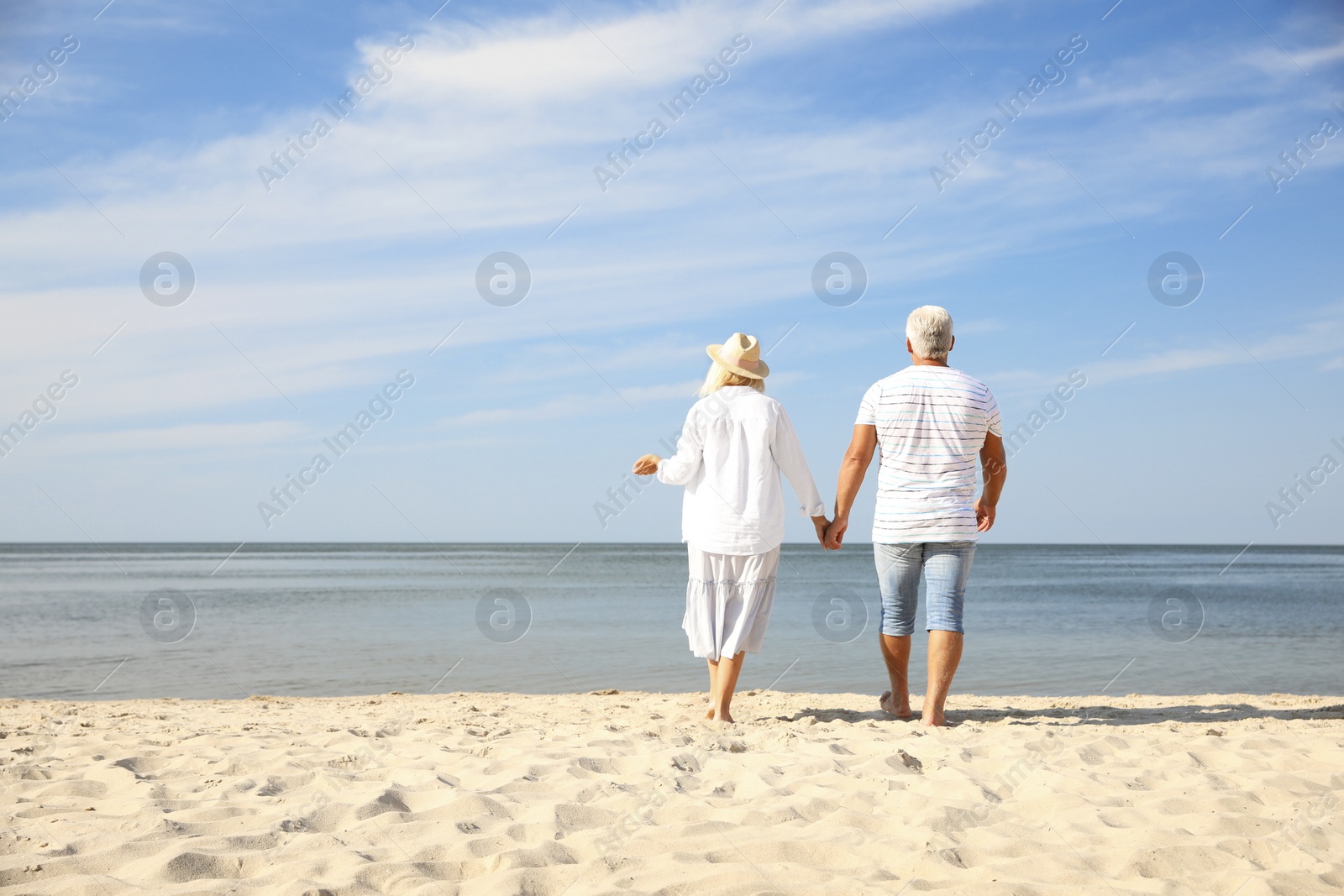 Photo of Mature couple spending time together on sea beach, back view