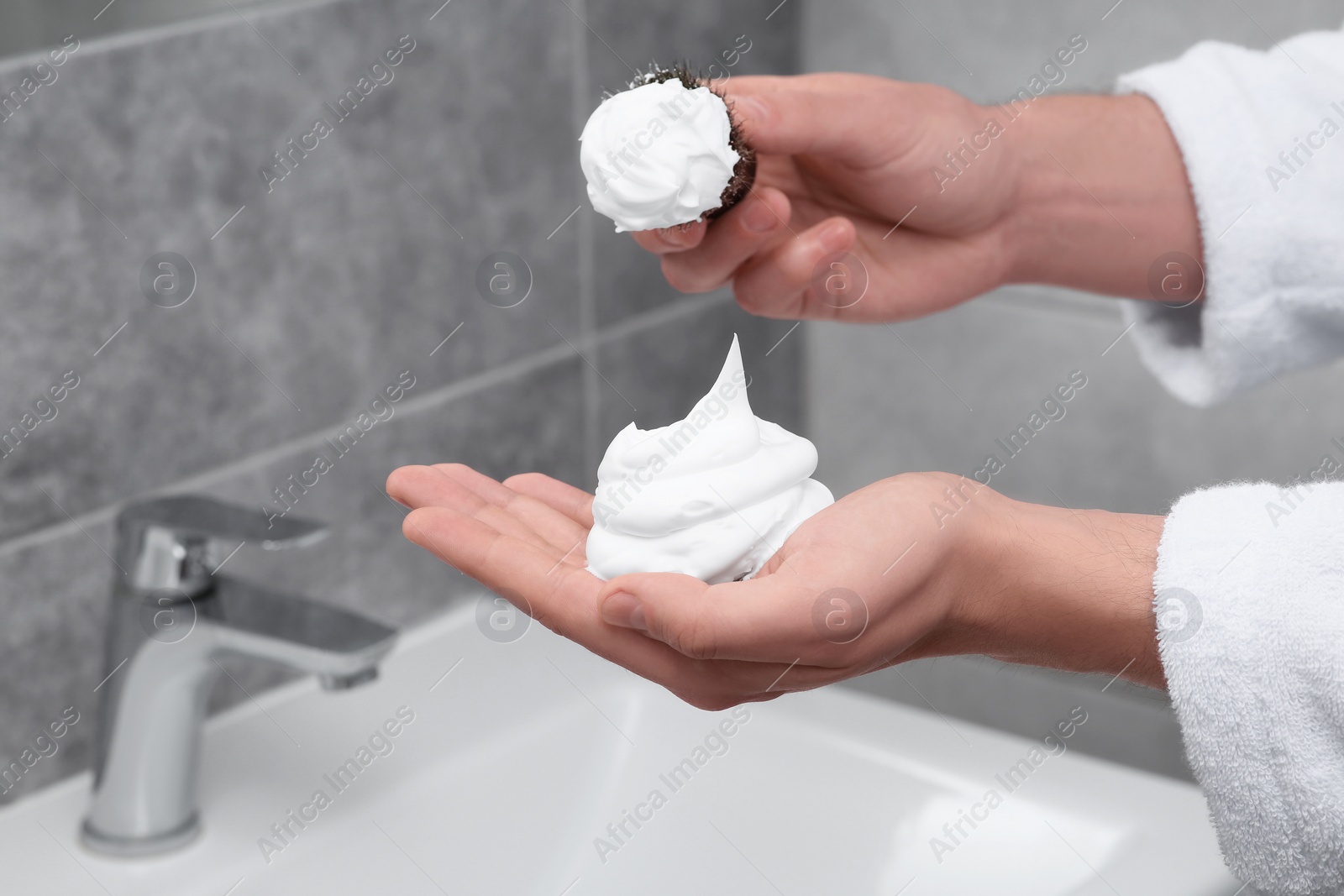 Photo of Man applying shaving foam onto brush in bathroom, closeup