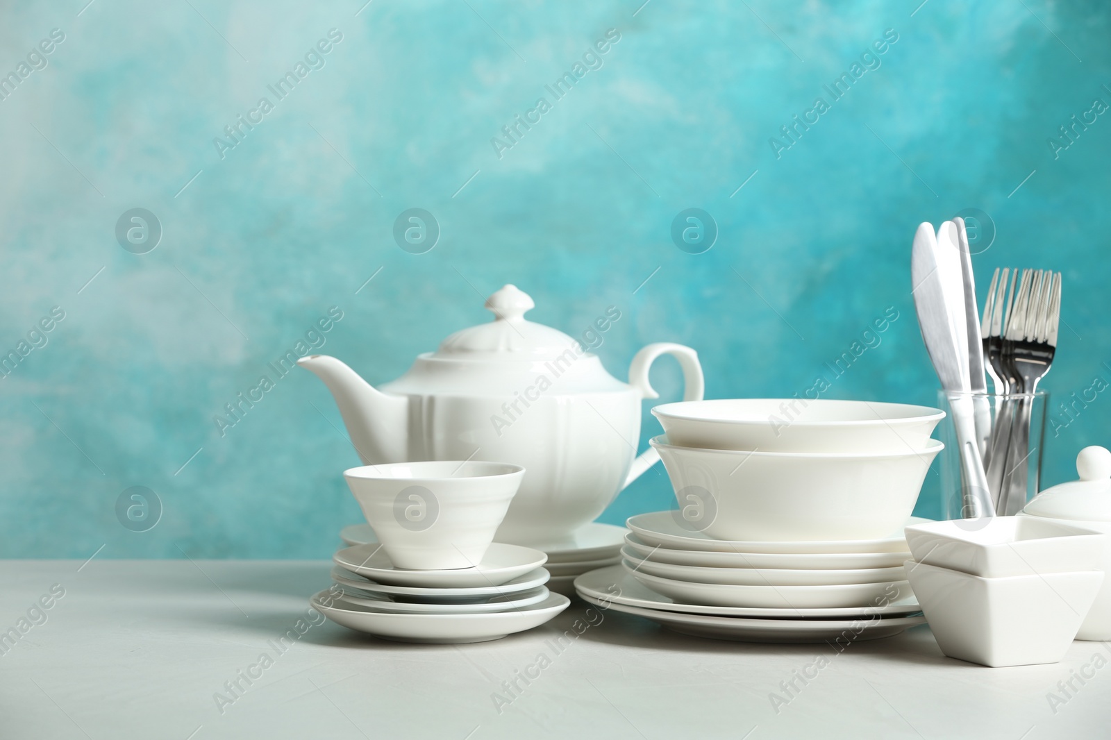 Photo of Set of clean dishes on table against blurred background. Space for text