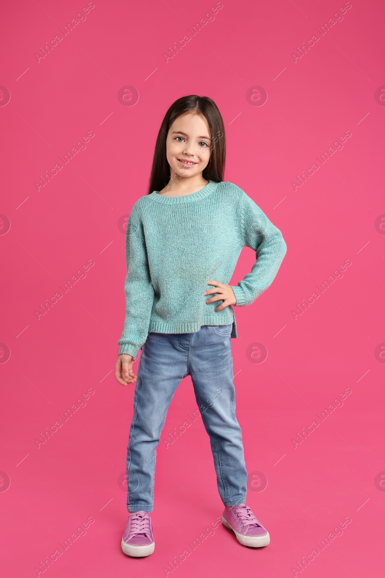 Photo of Cute little girl posing on pink background