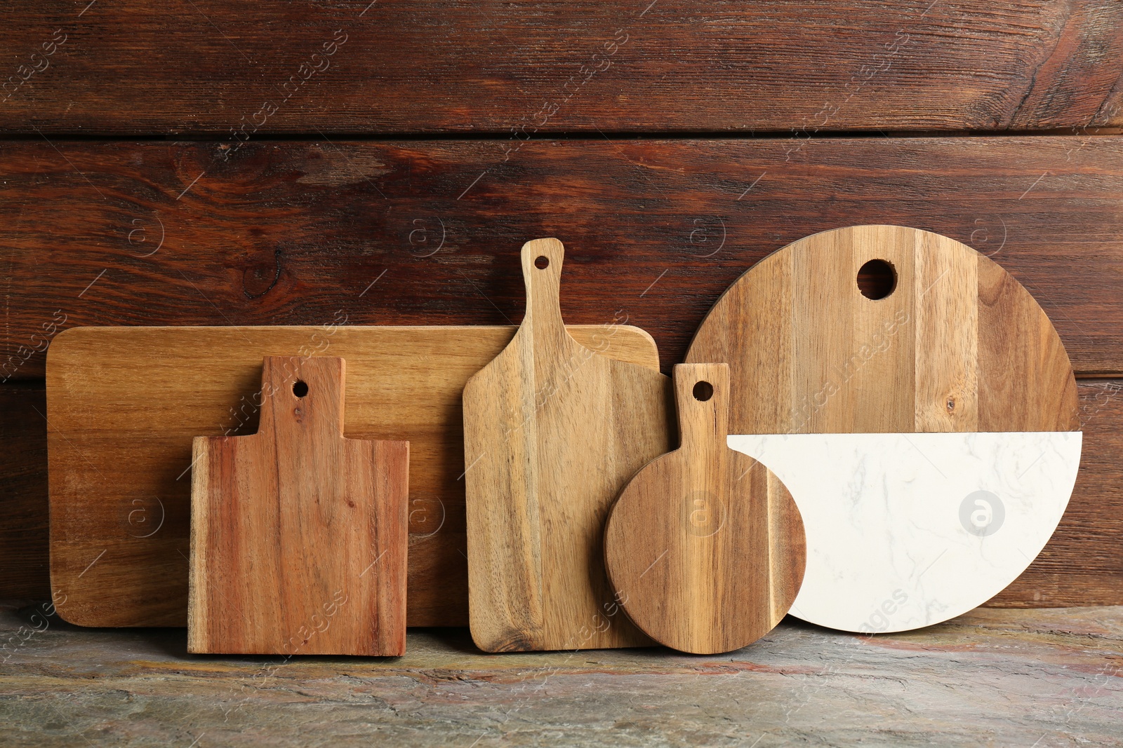 Photo of Set of different cutting boards on table near wooden wall, space for text