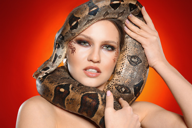 Beautiful woman with boa constrictor on bright colorful  background