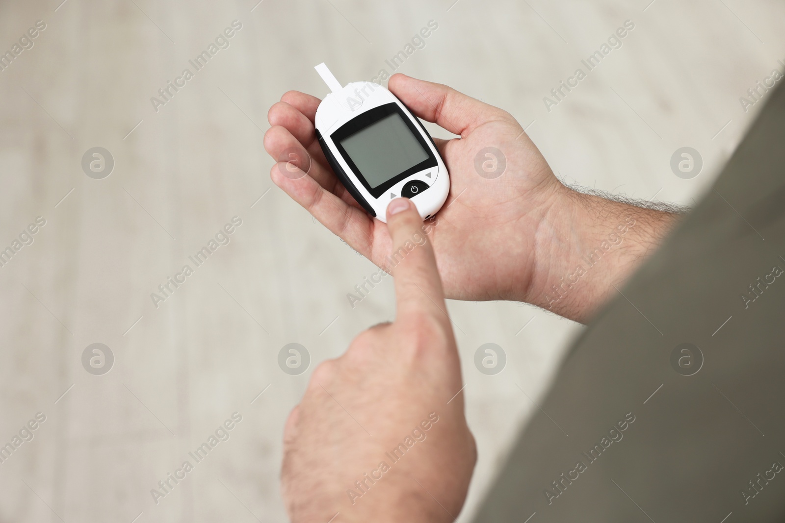 Photo of Diabetes test. Man using glucometer on blurred background, closeup. Space for text