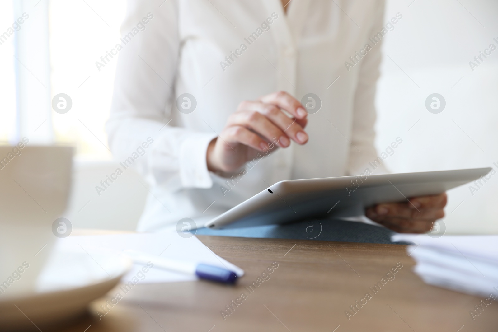 Photo of Businesswoman working with modern tablet at wooden table in office, closeup