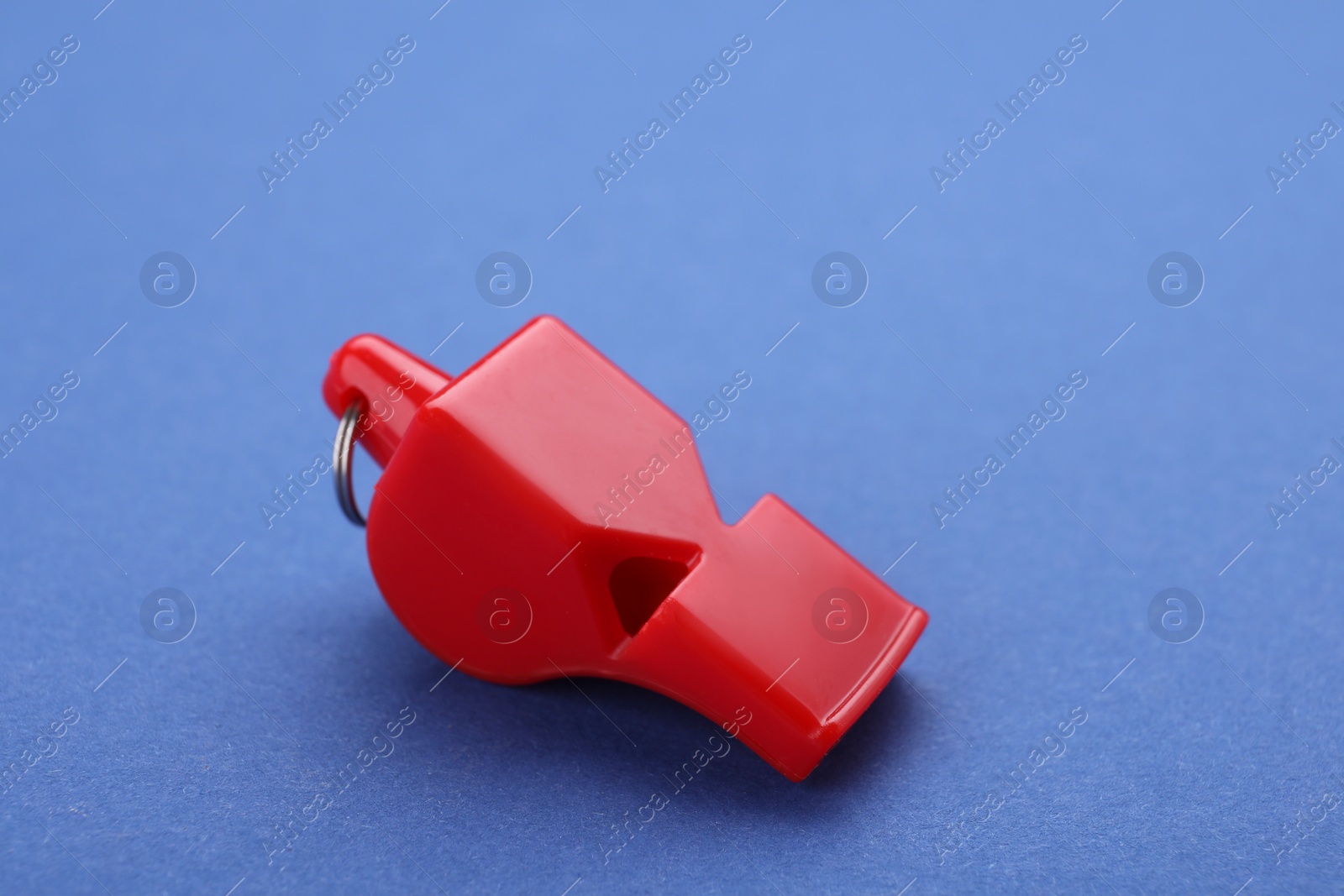 Photo of One red whistle on blue background, closeup