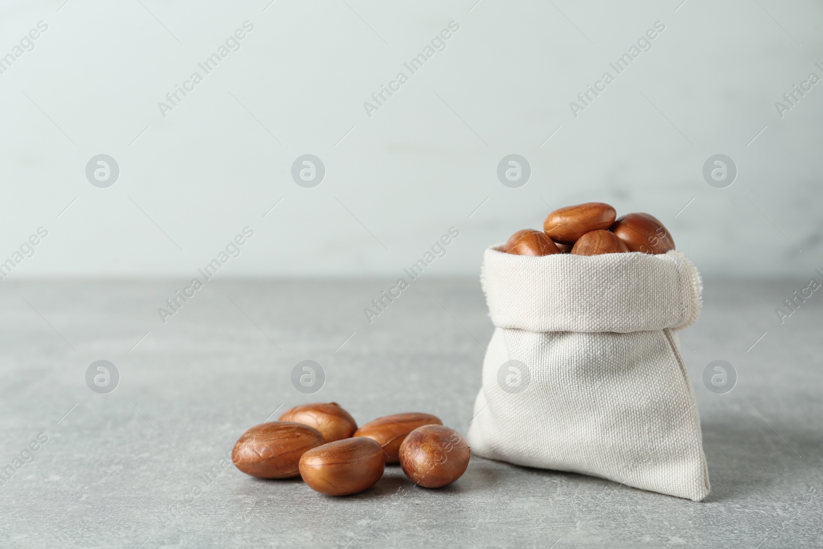 Photo of Sackcloth bag with jackfruit seeds on light grey table. Space for text