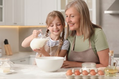 Photo of Happy grandmother with her granddaughter cooking together in kitchen