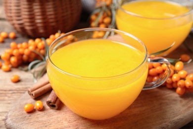 Fresh sea buckthorn tea on wooden board, closeup