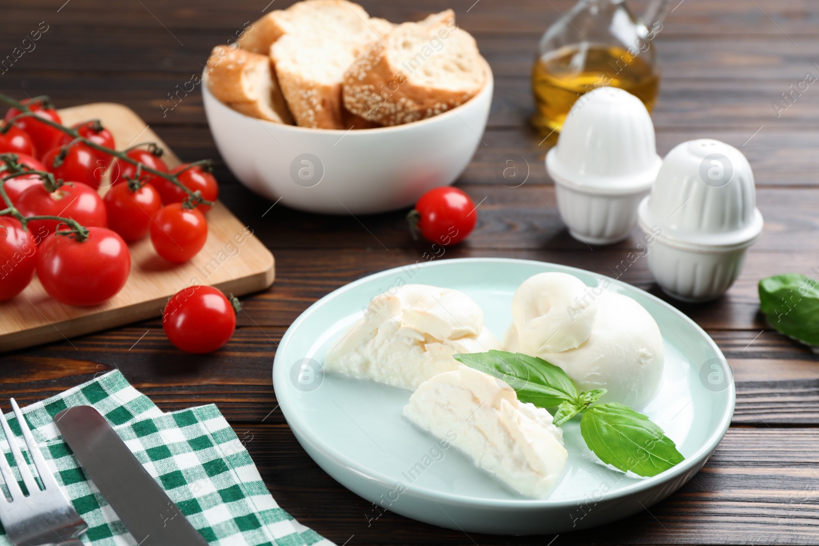 Photo of Delicious burrata cheese with basil served on wooden table