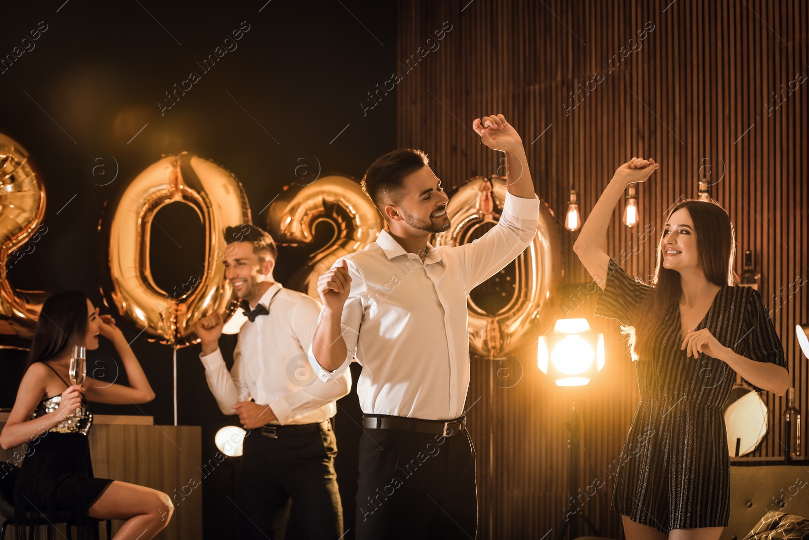 Photo of Young people celebrating New Year in club. Golden 2020 balloons on background