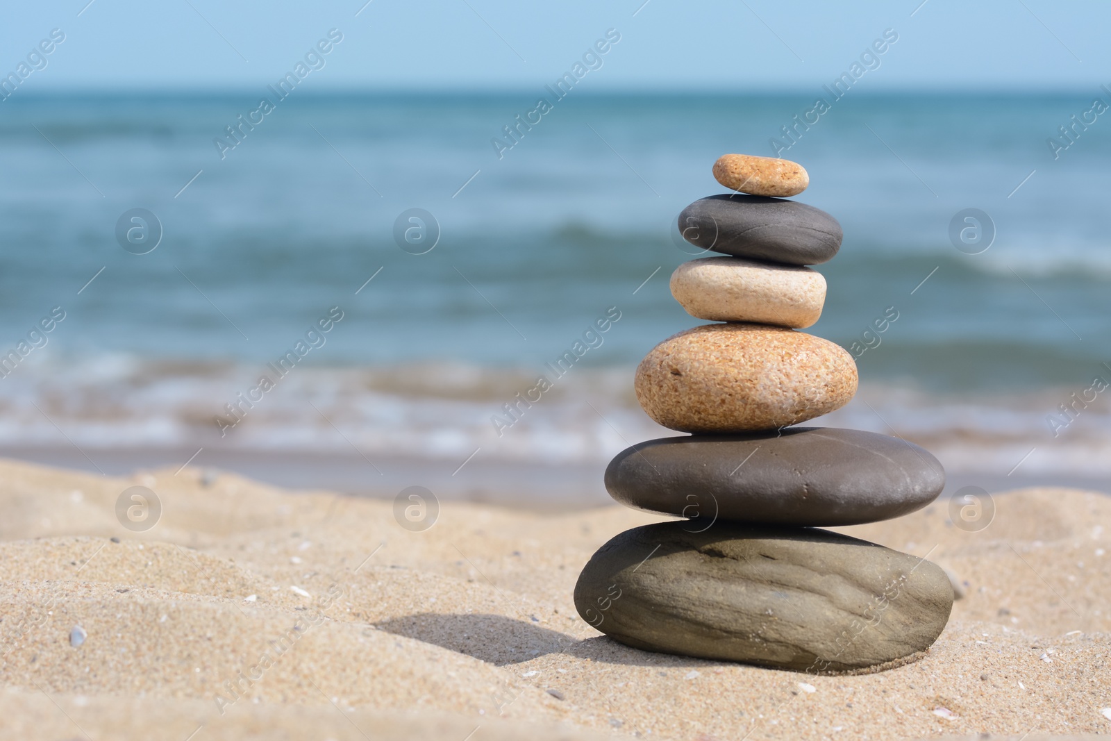 Photo of Stack of stones on sandy beach near sea, space for text