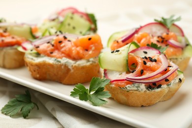 Photo of Tasty canapes with salmon served on white wooden table, closeup