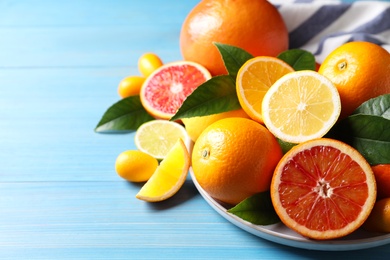 Photo of Different citrus fruits on light blue wooden table, closeup