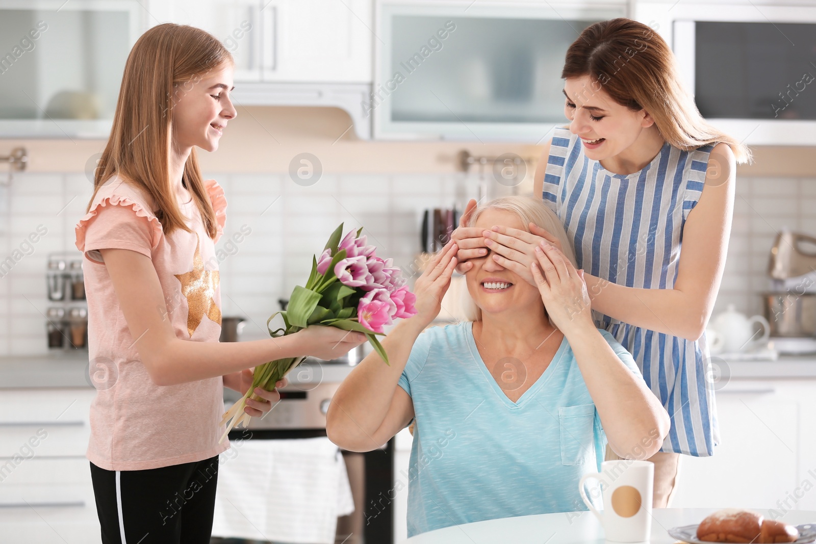 Photo of Young woman with daughter congratulating mature family member at home. Happy Mother's Day