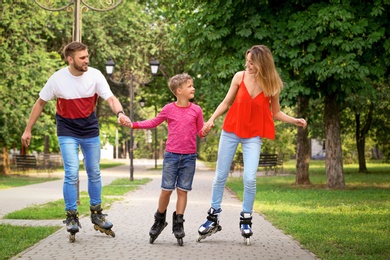 Photo of Young happy family roller skating in summer park