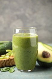 Photo of Delicious green juice and fresh ingredients on light blue wooden table