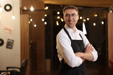 Photo of Professional hairdresser wearing apron in beauty salon, space for text