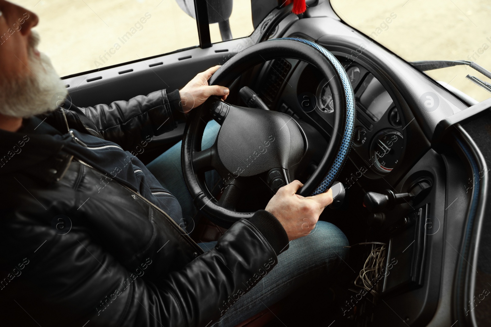 Photo of Mature driver sitting in cab of modern truck, closeup view