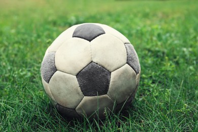 Photo of Dirty soccer ball on fresh green grass outdoors, closeup