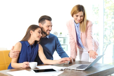 Photo of Female real estate agent working with couple in office