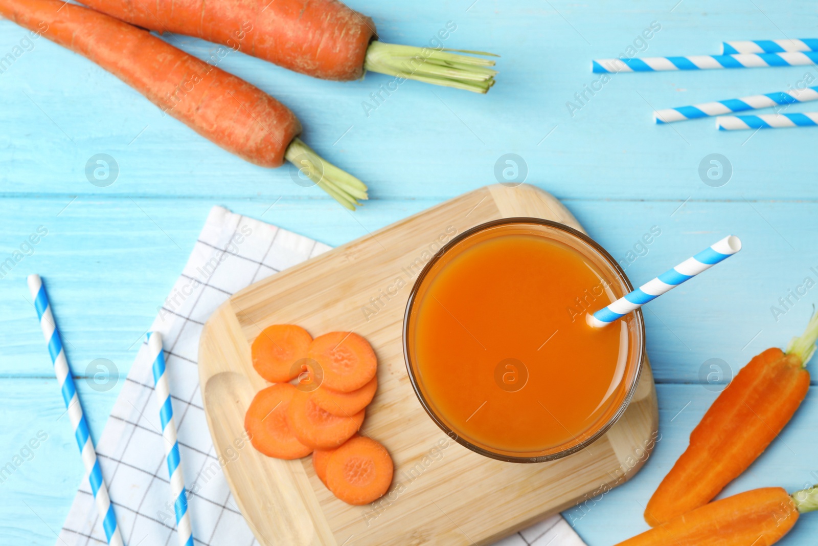 Photo of Flat lay composition with carrots and juice on light blue wooden table