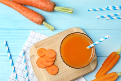 Flat lay composition with carrots and juice on light blue wooden table