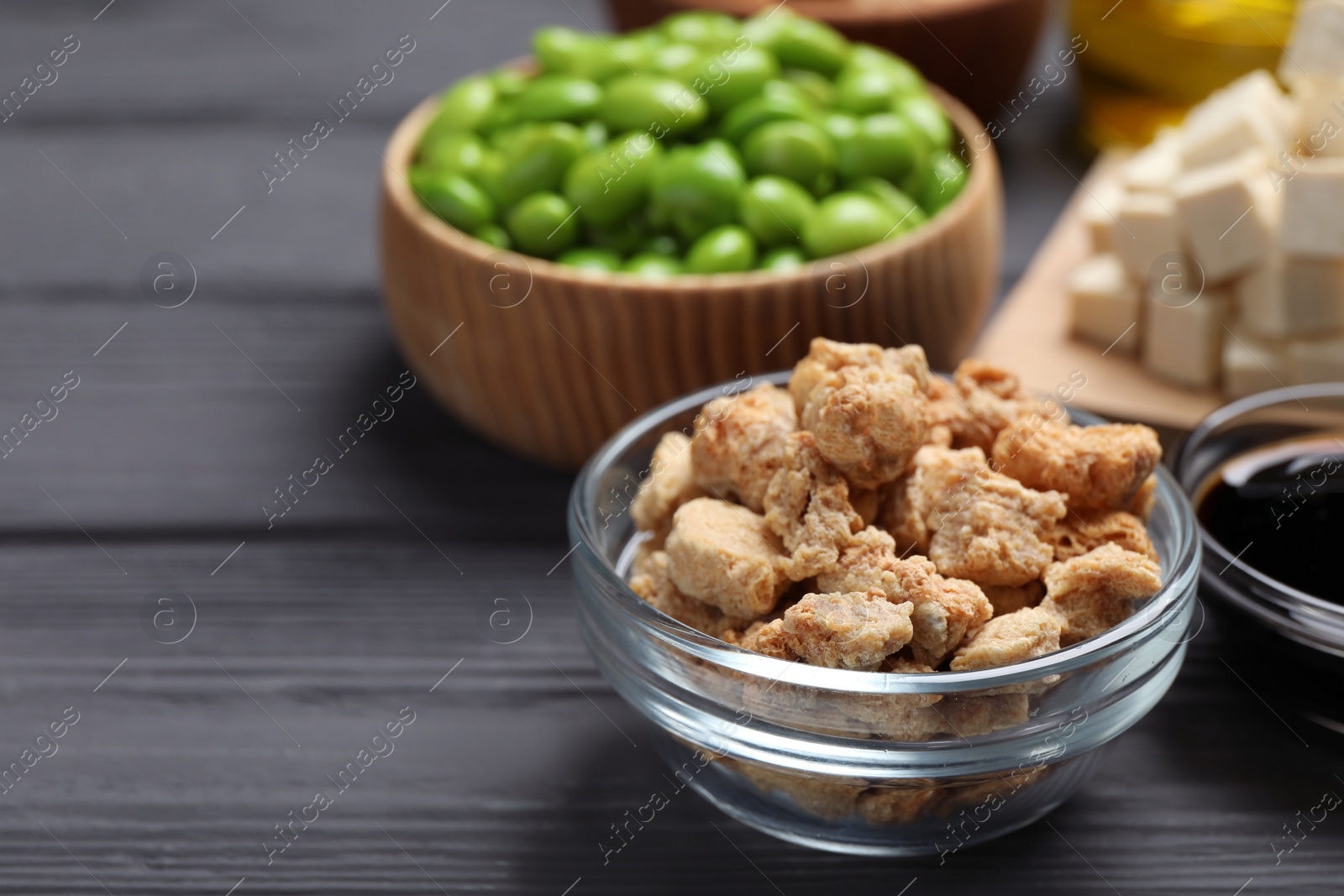 Photo of Dehydrated soy meat and other organic products on grey wooden table, closeup. Space for text