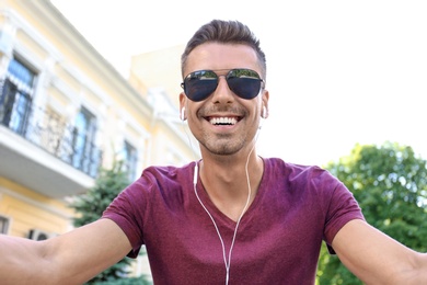 Young man in sunglasses taking selfie outdoors