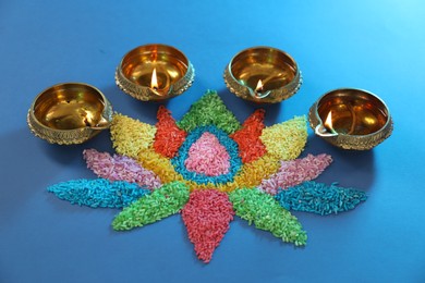 Photo of Diwali celebration. Diya lamps and colorful rangoli on blue background