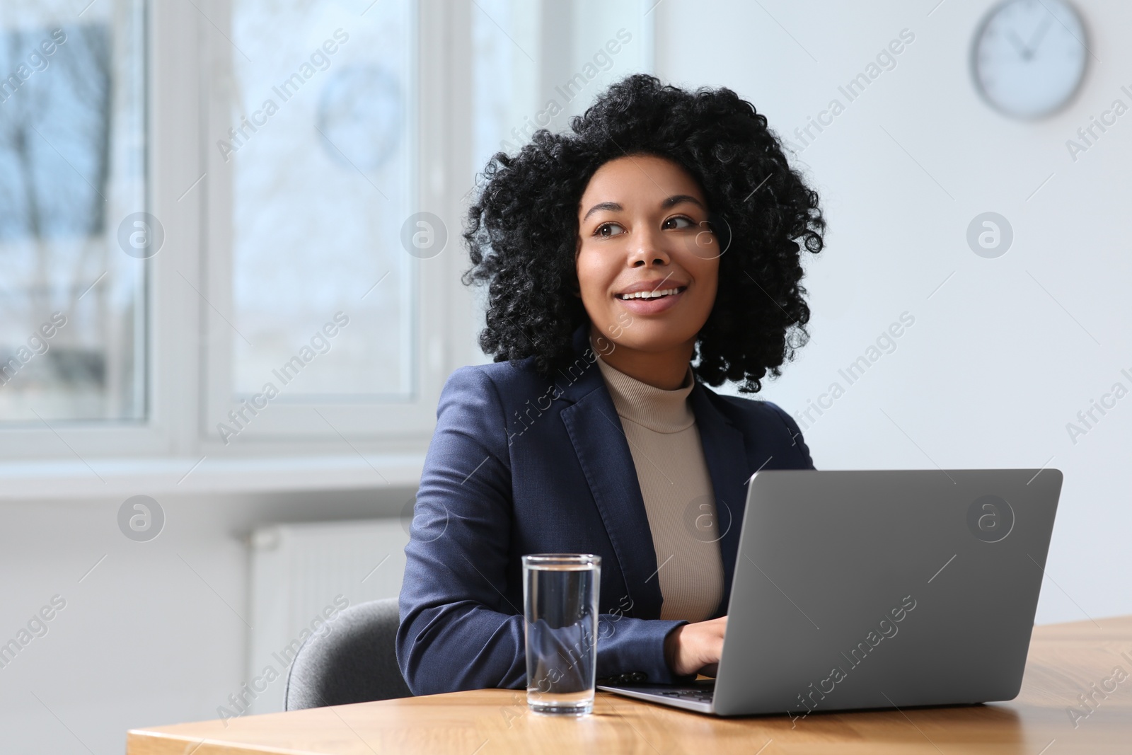 Photo of Young woman working on laptop at table in office