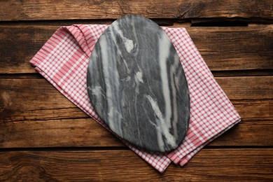 Photo of Red checkered kitchen towel with marble board on wooden table, top view