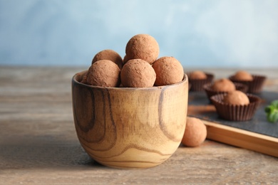 Photo of Bowl with chocolate truffles on wooden table
