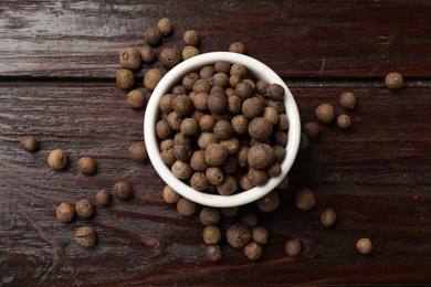 Photo of Dry allspice berries (Jamaica pepper) in bowl on wooden table, top view