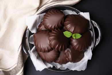 Photo of Delicious chocolate covered marshmallows with mint on black table, flat lay