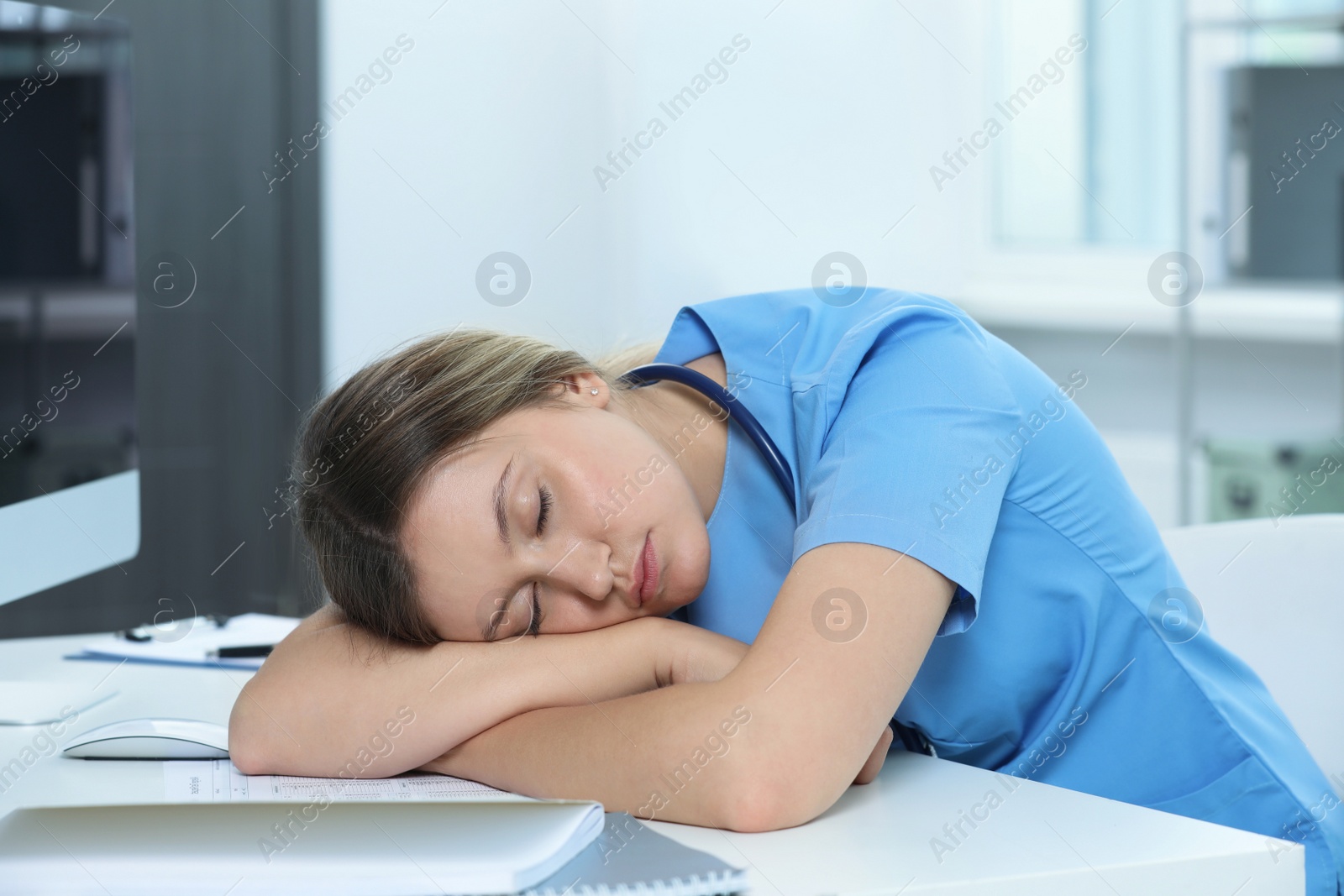 Photo of Exhausted doctor sleeping at workplace in hospital