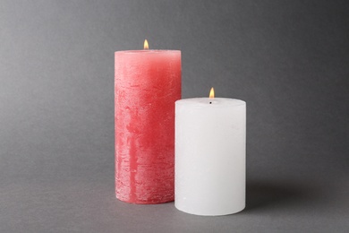 Photo of Stylish color burning candles on grey background
