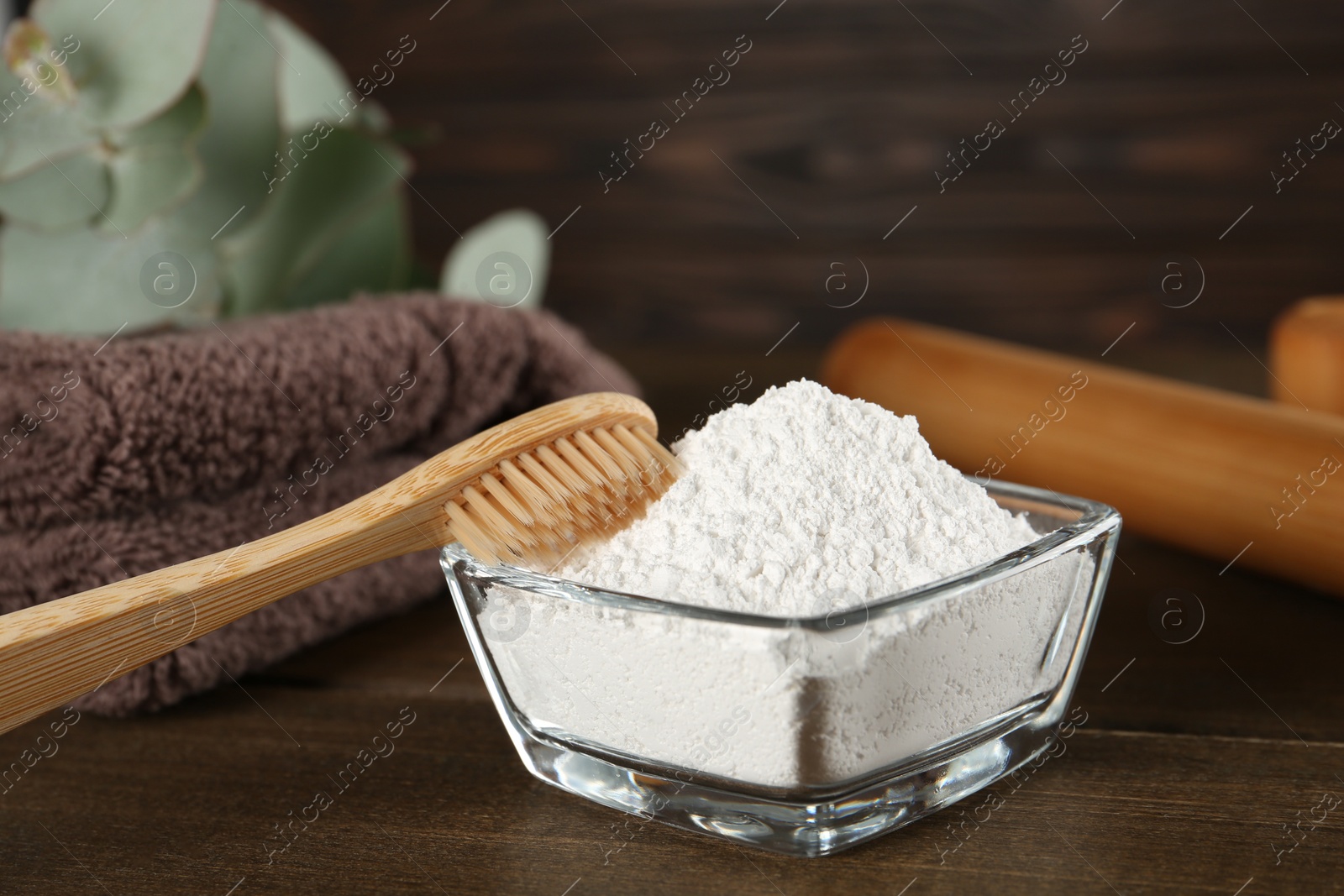 Photo of Tooth powder, brush and towel on wooden table, closeup