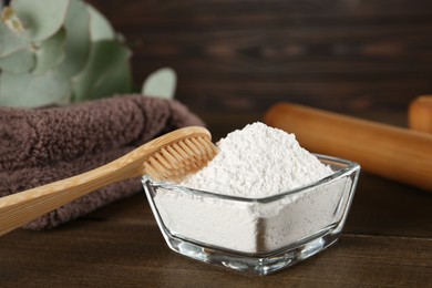 Photo of Tooth powder, brush and towel on wooden table, closeup
