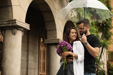 Photo of Young couple with umbrella enjoying time together under rain on city street, space for text
