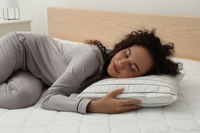 Photo of Young African American woman sleeping on bed with comfortable mattress and pillow at home