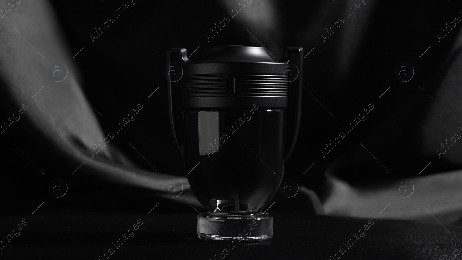 Photo of Luxury bottle of perfume on black silk, closeup