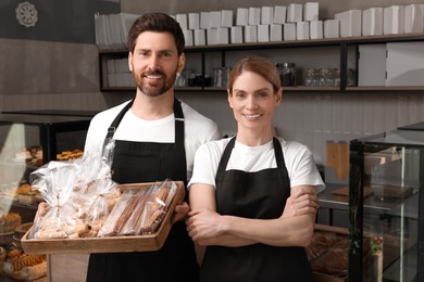 Happy sellers with pastries in bakery shop