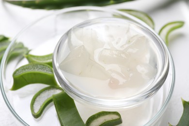 Aloe vera gel and slices of plant on white background, closeup