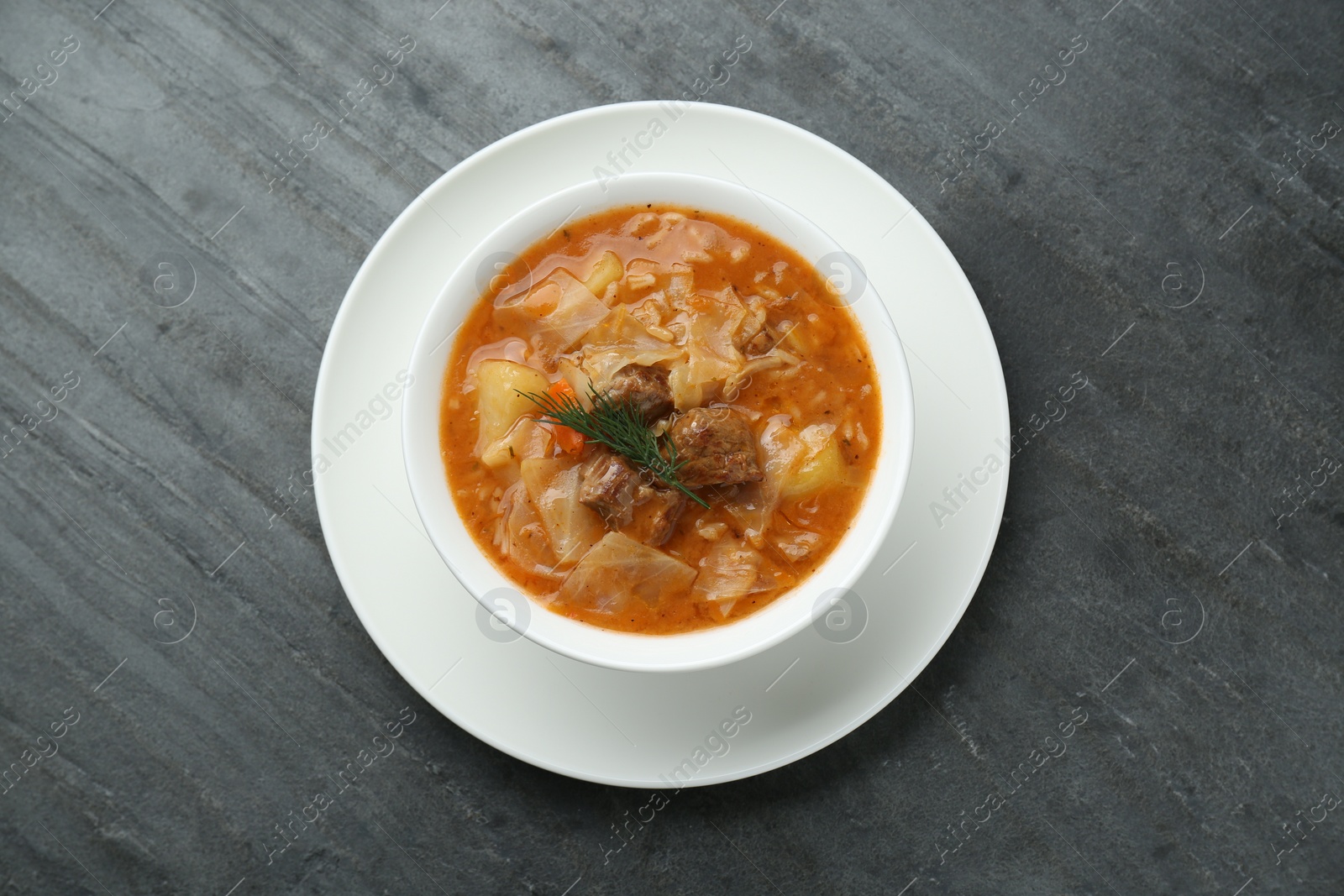 Photo of Tasty cabbage soup with meat, carrot and dill on black table, top view
