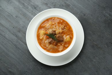 Tasty cabbage soup with meat, carrot and dill on black table, top view