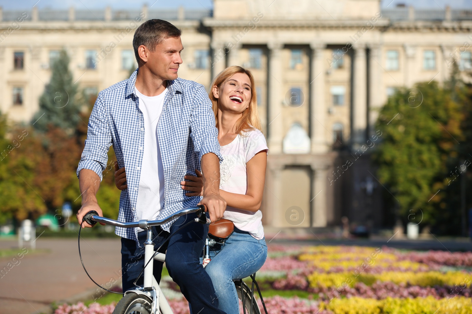 Photo of Happy couple riding bicycle outdoors on sunny day